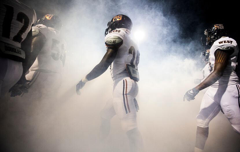 West Mesquite football players enter the field in a cloud of smoke before a high school...