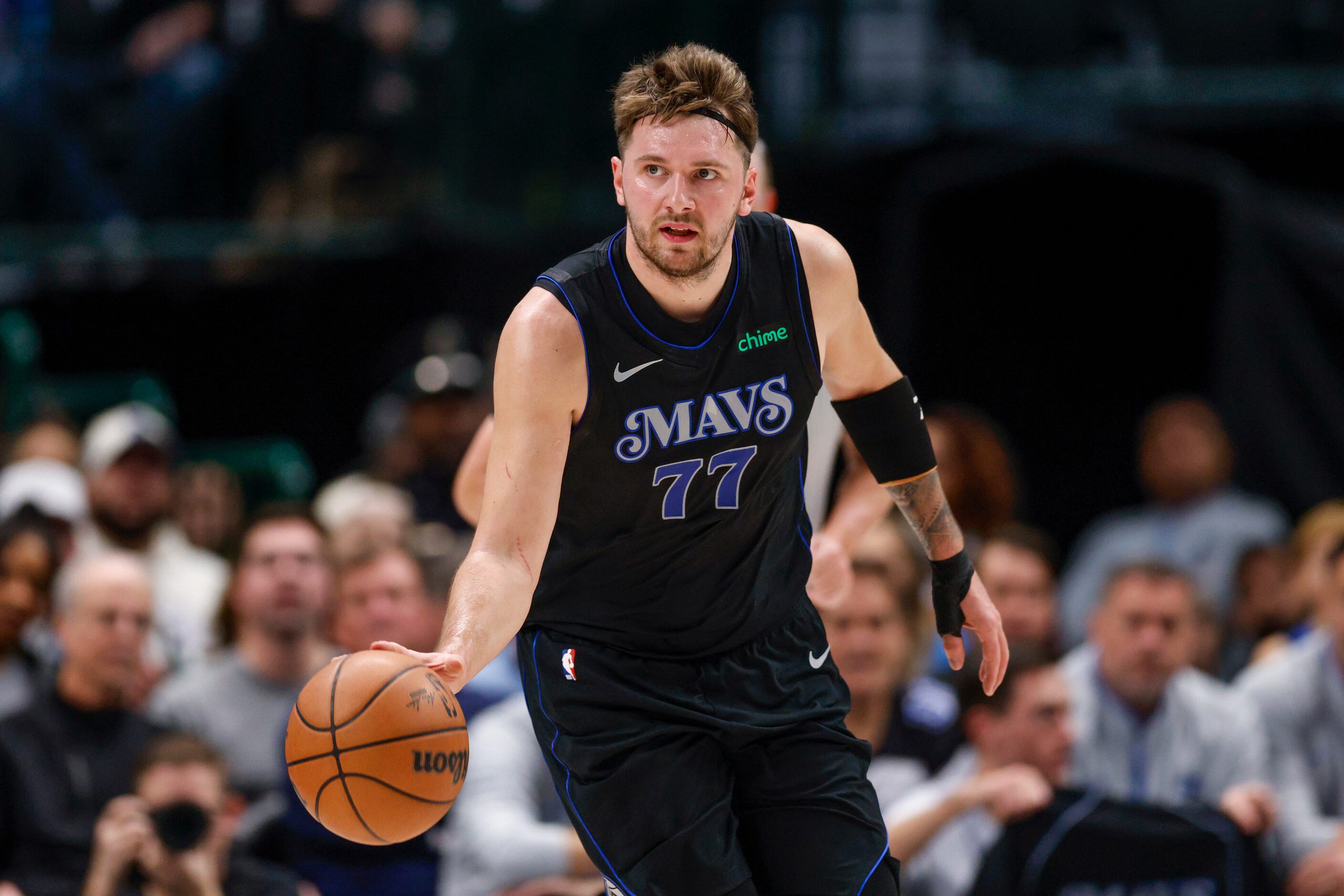 Dallas Mavericks guard Luka Doncic (77) wears a headband as he dribbles down court during...