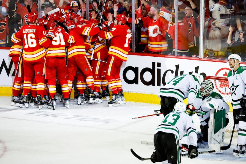 Dallas Stars goalie Jake Oettinger, second from right, is consoled by teammates as Calgary...
