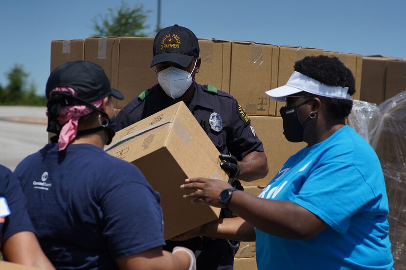 Three people lift boxes as part of the Concord Church Concord Cares Initiative, which helps...