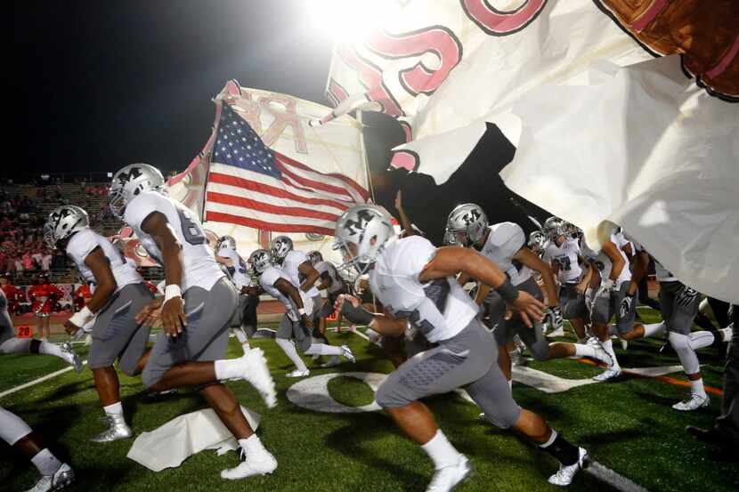 Arlington Martin players run onto the fire prior to their high school football game against...