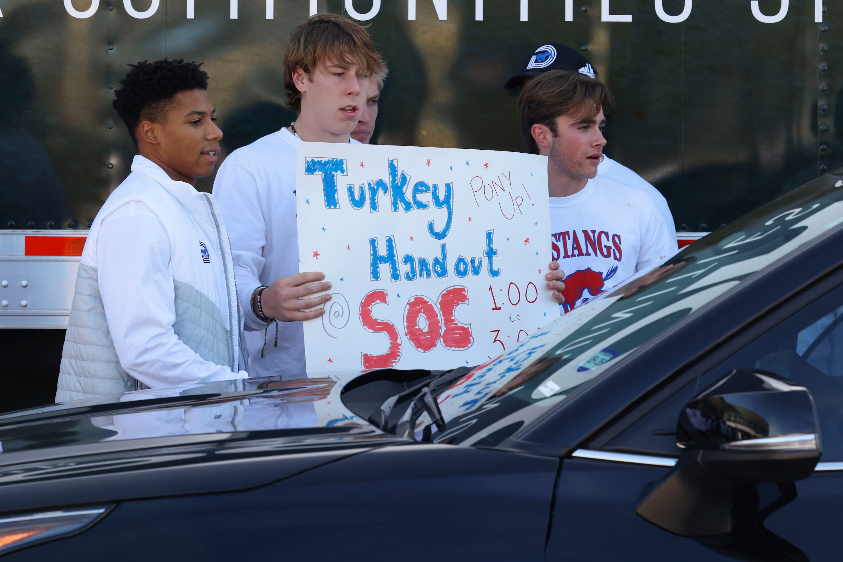 Southern Methodist University football players hold a sign as they hand out turkey to...