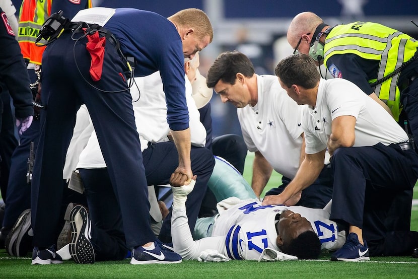 Dallas Cowboys head coach Jason Garrett checks on wide receiver Allen Hurns (17) as he...