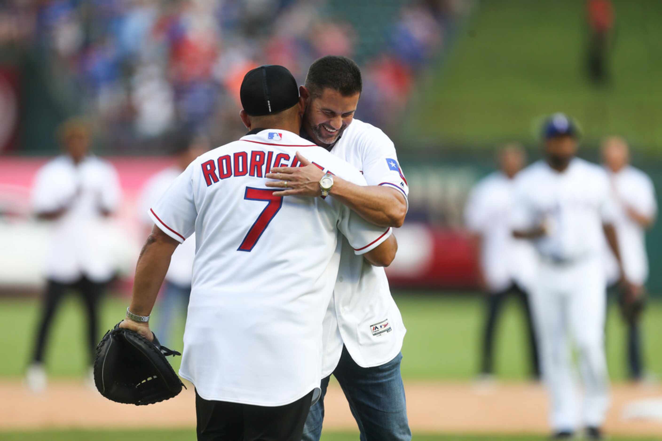 Former Texas Rangers catcher Ivan "Pudge" Rodriguez embraces former infielder Michael Young...