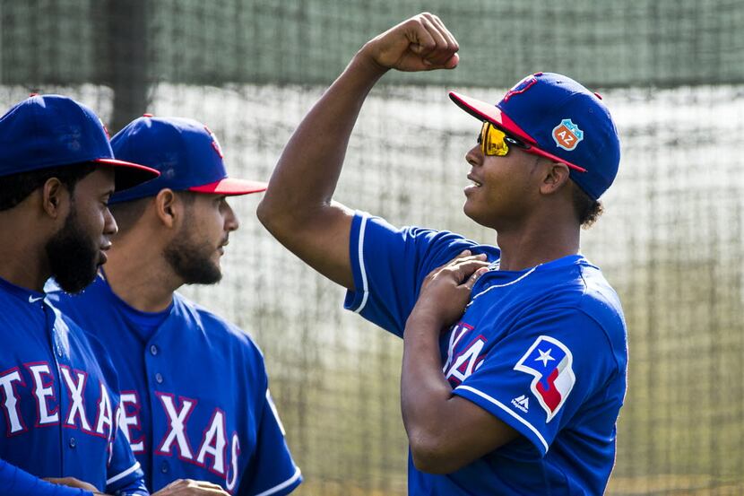 Texas Rangers pitcher Jose Leclerc flexes for fellow pitchers Yohander Mendez (left) and...