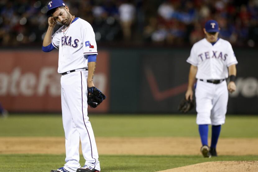 Texas Rangers' Mike Adams adjusts his cap in the eighth inning of a baseball game against...