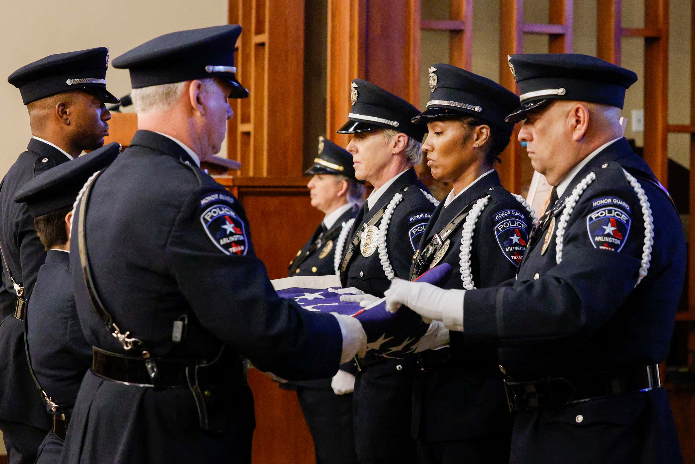 Members of the Arlington police honor guard perform a flag fold ceremony during a funeral...