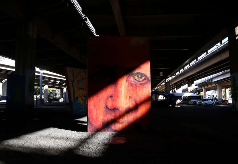 Afternoon sunlight pouring between spans of I-345 light up murals between Canton St. and...