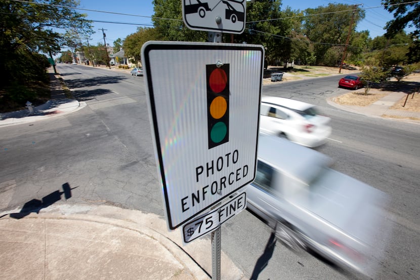 A photo enforced sign warns drivers on Peak Street of red-light traffic cameras at an...