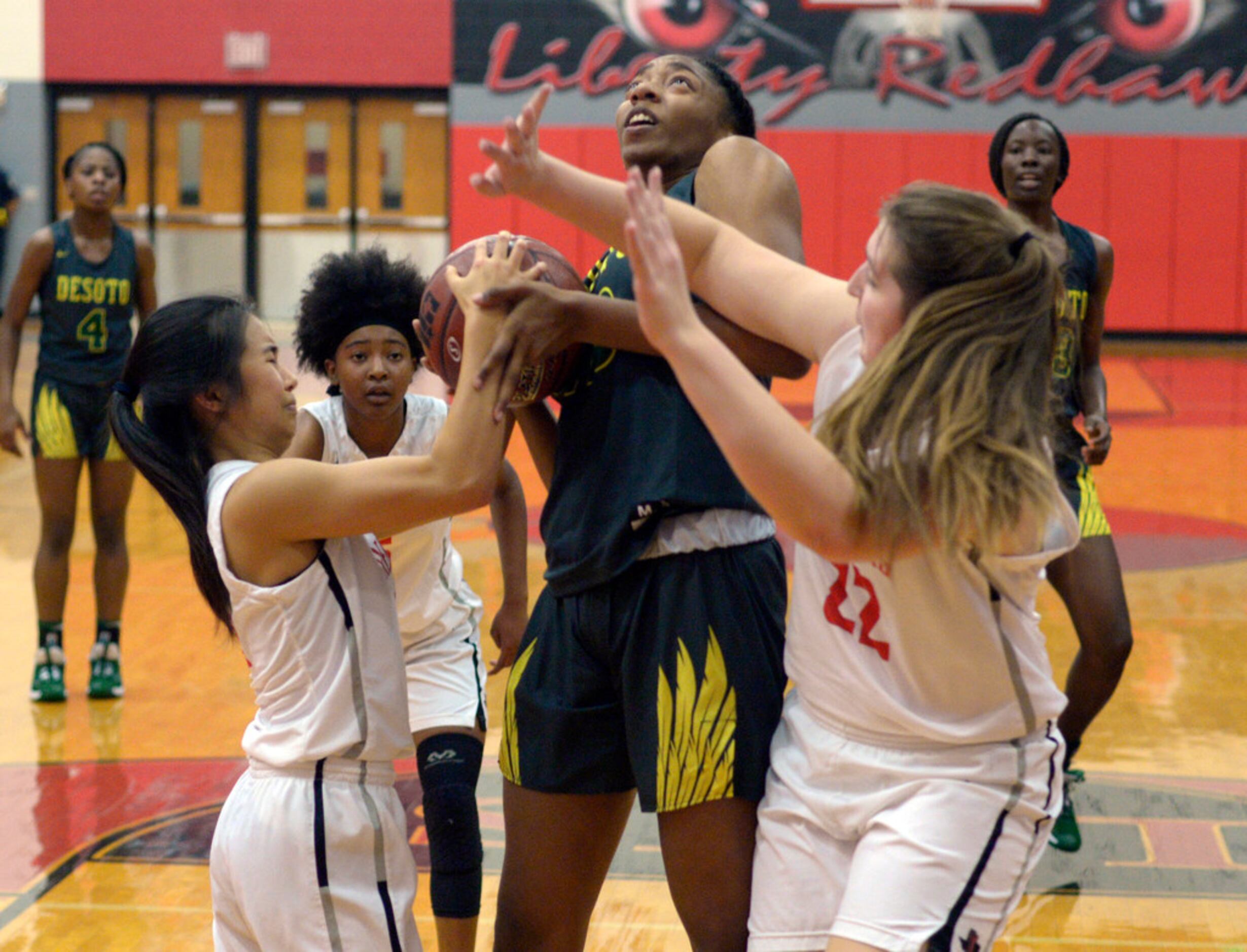 Liberty's Kamen Wong, left, and Kyla Crawford (22) try to tie up DeSoto's Tionna Herron in...