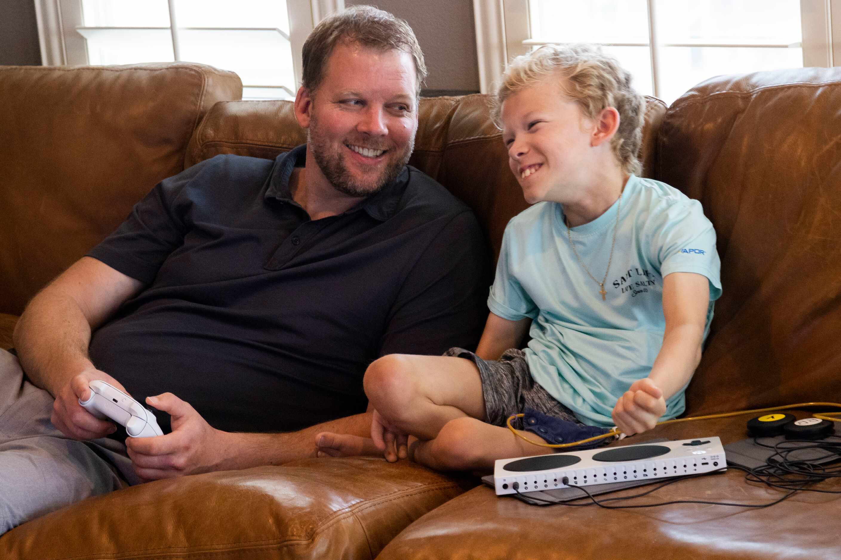 Doug Woleben (left) and Will Woleben, 11, react while playing NHL on their Xbox at their...