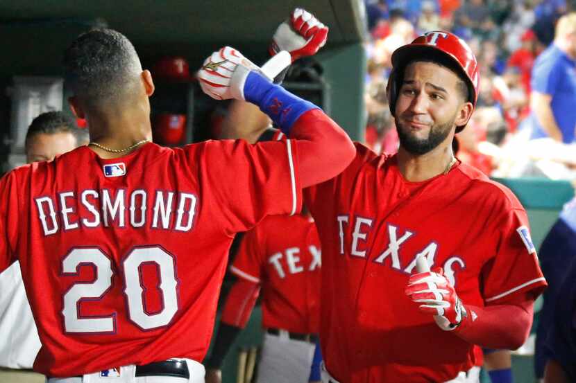Texas Rangers right fielder Nomar Mazara (30) is greeted by Ian Desmond (20) in the dugout...