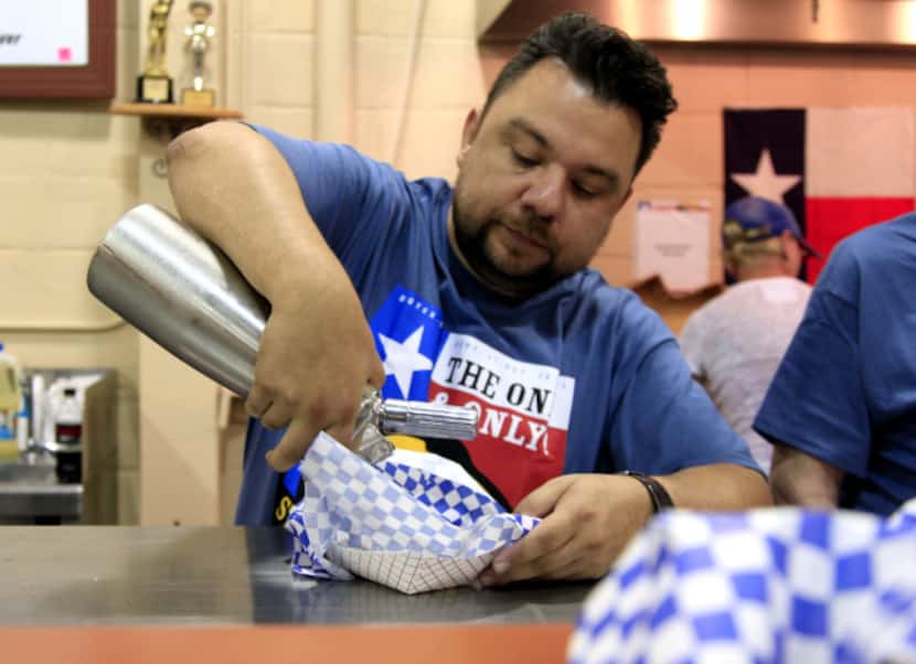 Abel Gonzales puts whipped cream on Awesome Deep Fried Nutella during the Big Tex Choice...