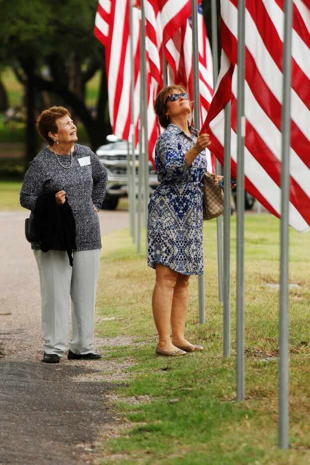 Elizabeth Ann Collins watches family friend Debbie Miller untangles the flag honoring her...