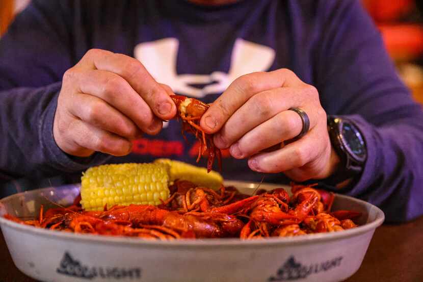 James Freeman removes crawfish meat from its shell during lunch at Big Fish Seafood Grill &...