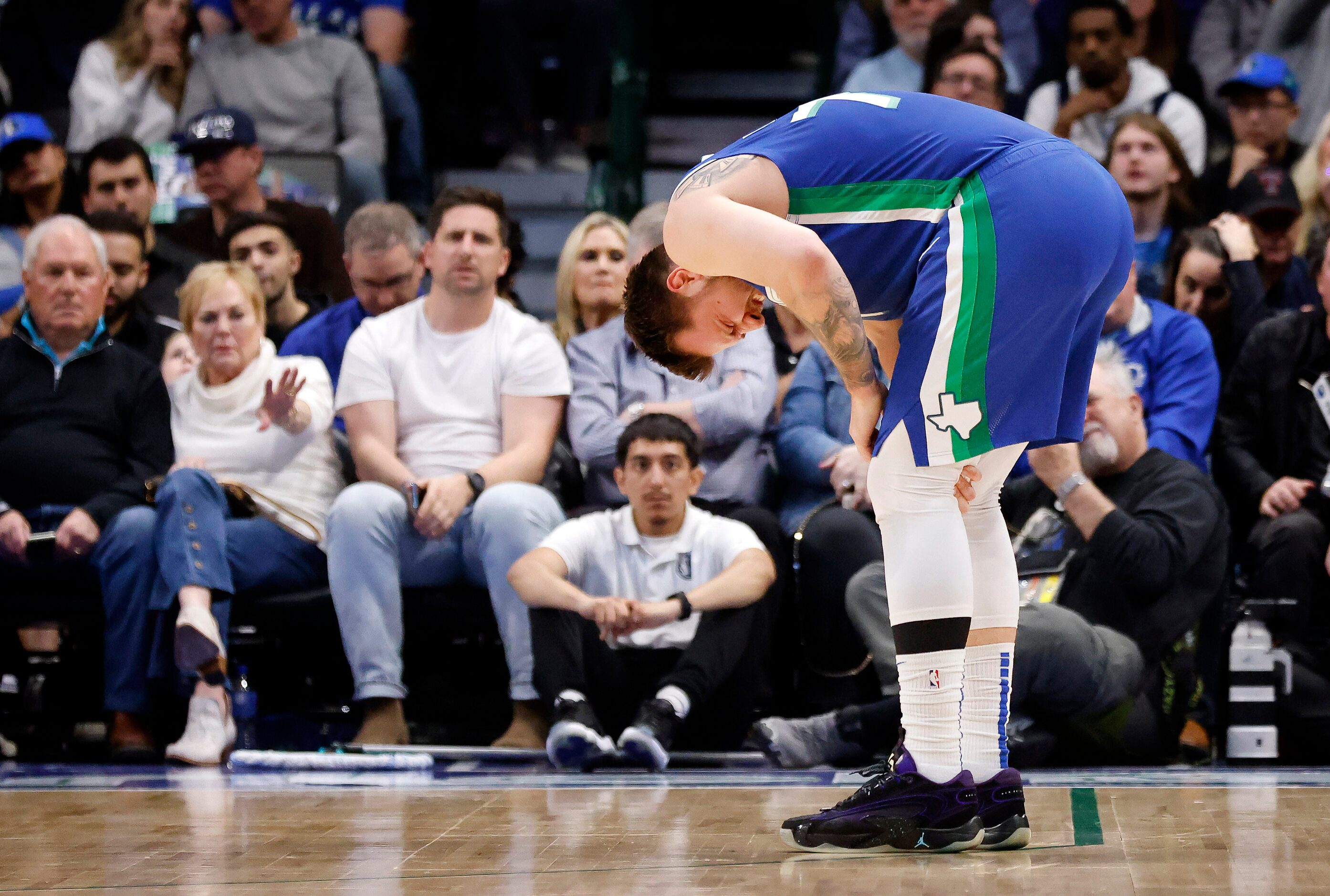 Dallas Mavericks guard Luka Doncic (77) holds his left knee after colliding with Sacramento...