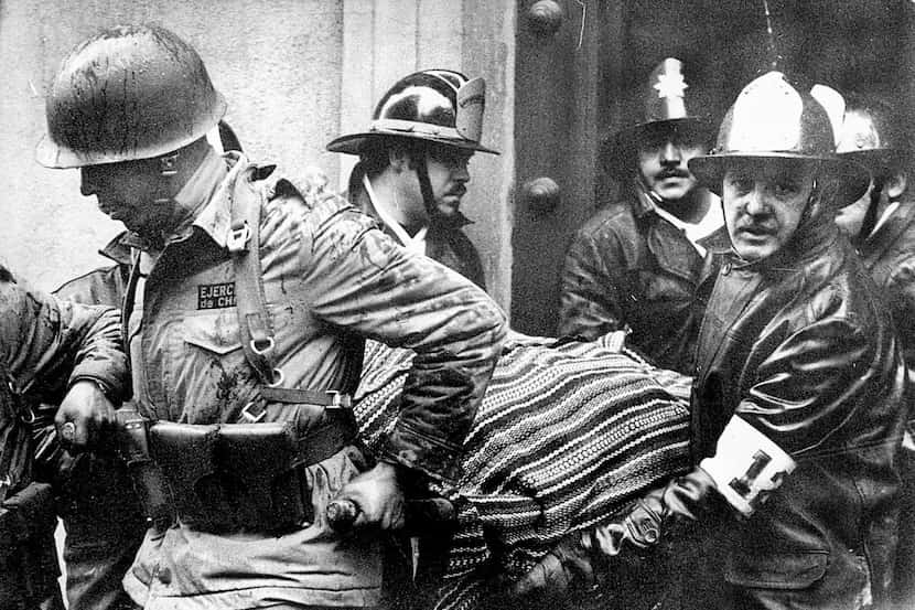 Soldiers and firefighters carry the body of Chilean President Salvador Allende, wrapped in a...