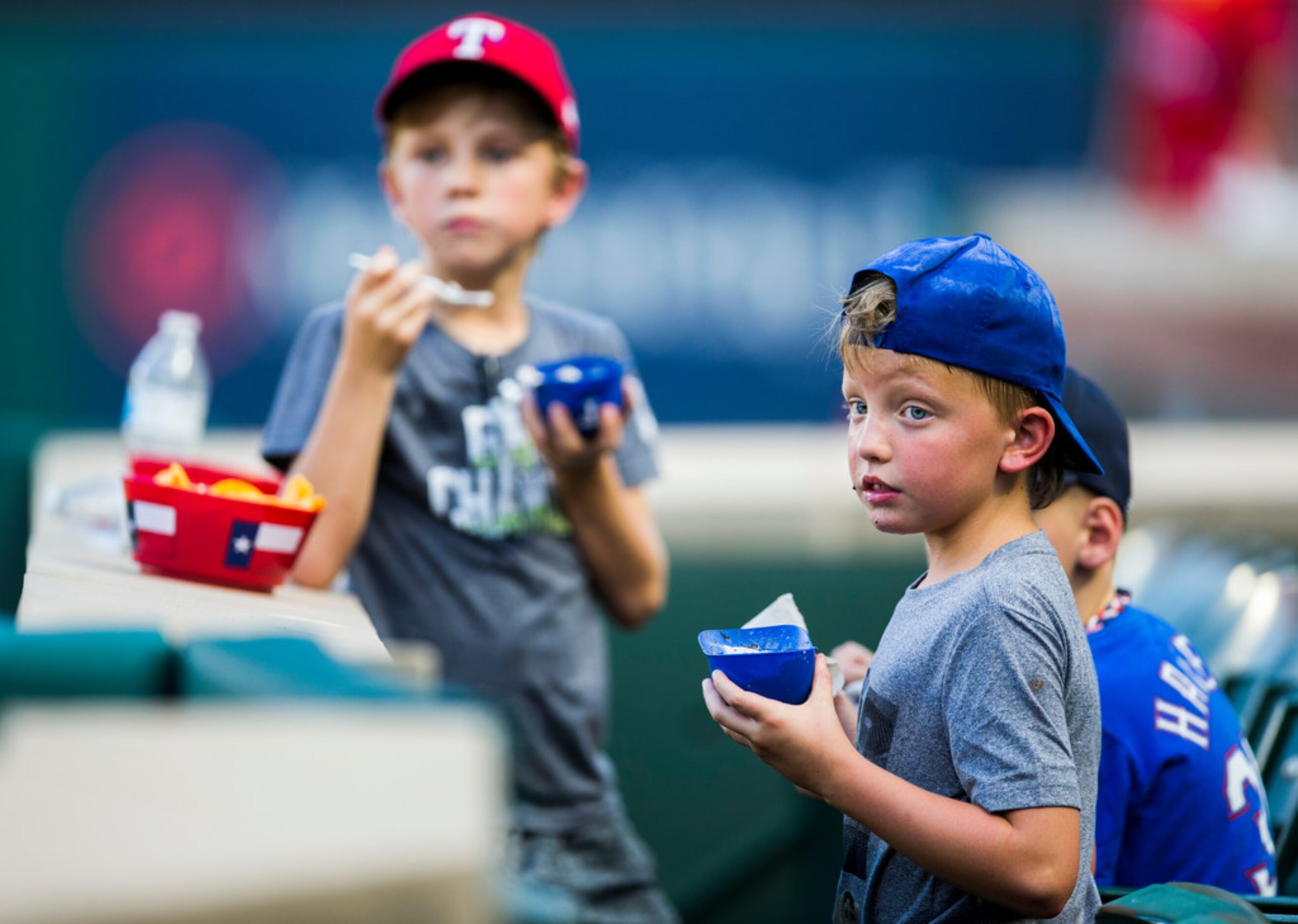 Boys eat ice cream out of mini batting helmets before an MLB game between the Texas Rangers...