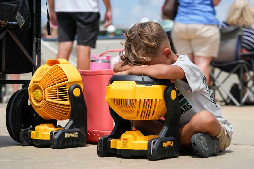 Braxton Hicks, 7, of Livingston, Texas, holds his face to a portable fan to cool off during...