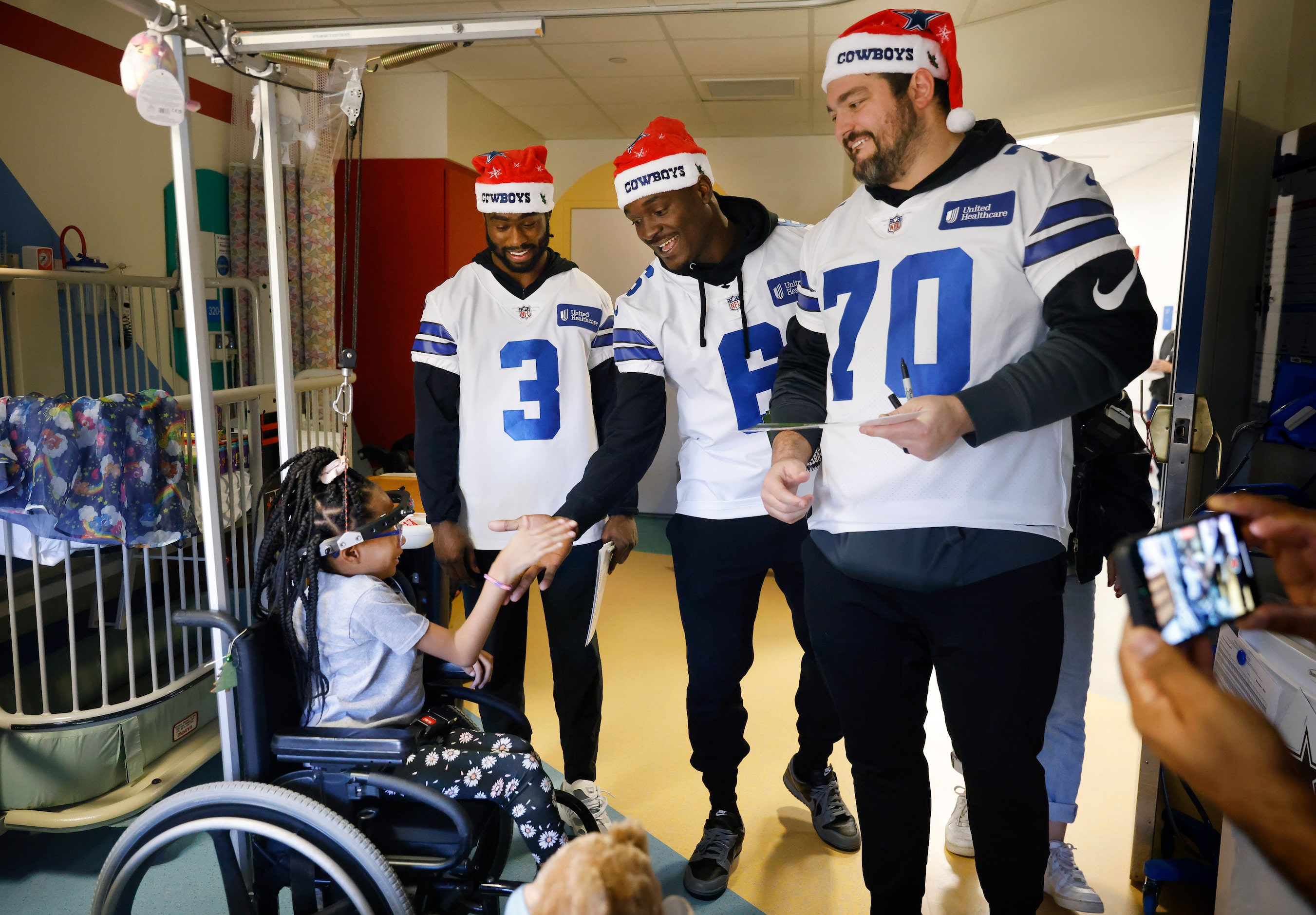 Serenitee Jackson (left) slpas hands with Dallas Cowboys safety Donovan Wilson (6) as he and...