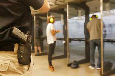  With his gun on his hip, instructor Mark Brushwiller watches shooters at the Frisco Gun...