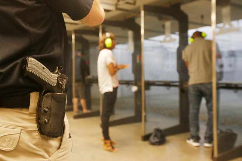  With his gun on his hip, instructor Mark Brushwiller watches shooters at the Frisco Gun...