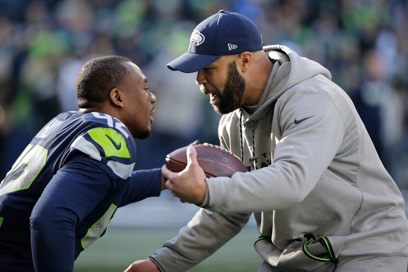 Seattle Seahawks defensive coordinator Kris Richard greets strong safety Delano Hill (42)...