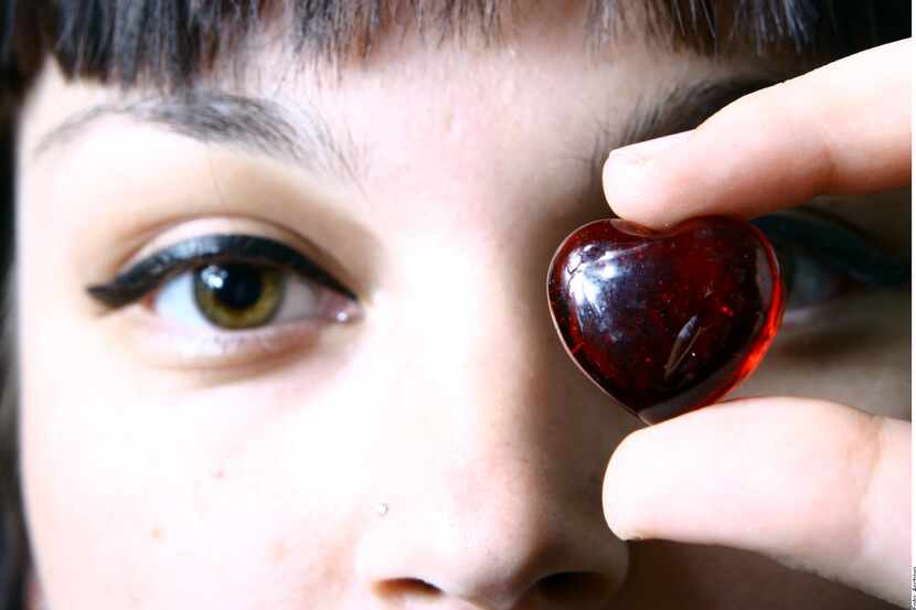 Una mujer con una piedra roja en forma de corazón en la mano.