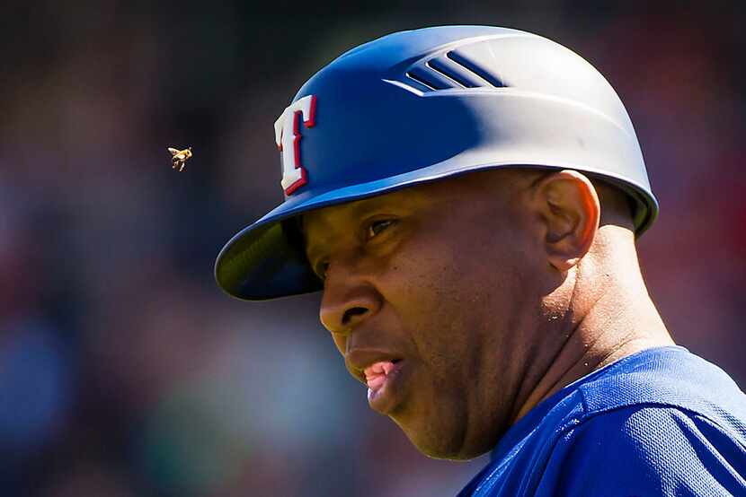 Texas Rangers third base coach Tony Beasley is buzzed by a bee during the second inning of a...