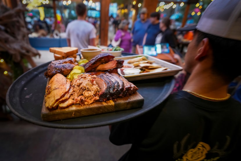 A board of signature smoked meats is delivered to a guest table at Smoky Rose restaurant. 