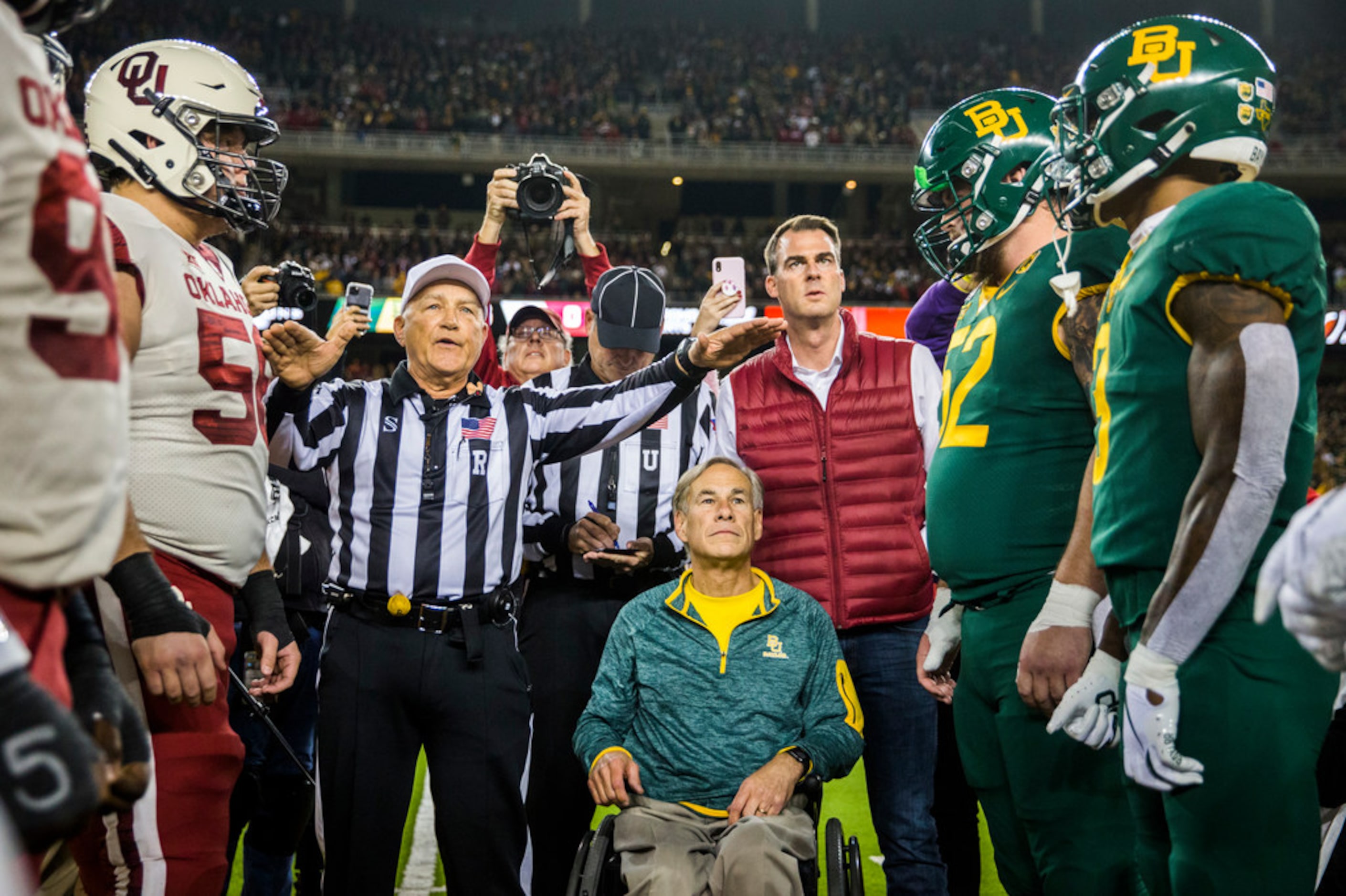 Texas Governor Greg Abbott (center) flips the coin before an NCAA football game between...