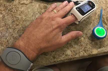 Dallas Morning News reporter Brad Townsend shows the thermometer, pulse oximeter and...
