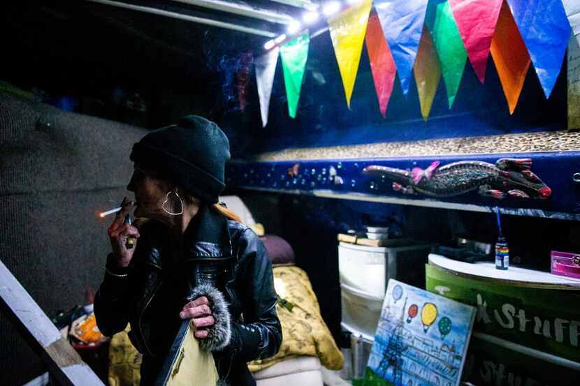 Kim Henderson smokes a cigarette in her encampment under an Interstate 35E bridge during the...