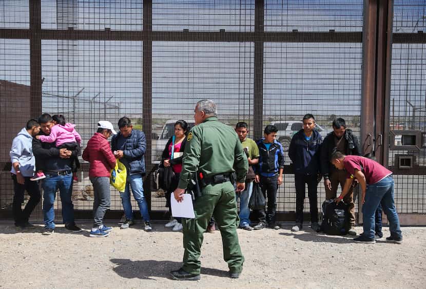 Central American asylum seekers wait as U.S. Border Patrol agents take them into custody...