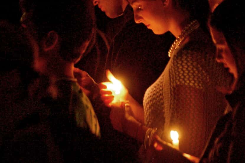 ORG XMIT: *S0410282280* A young woman holds her candle and listens to friends speak about...