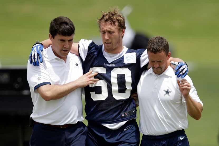 Cowboys linebacker Sean Lee is helped off the field by head athletic trainer Jim Maurer...