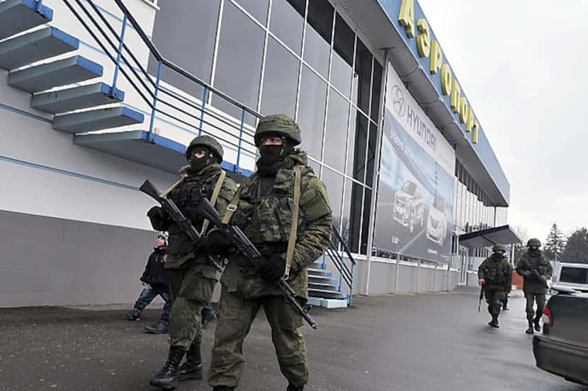 Unidentified troops patrol Friday outside the civilan airport in Simferopol, Crimea, in...