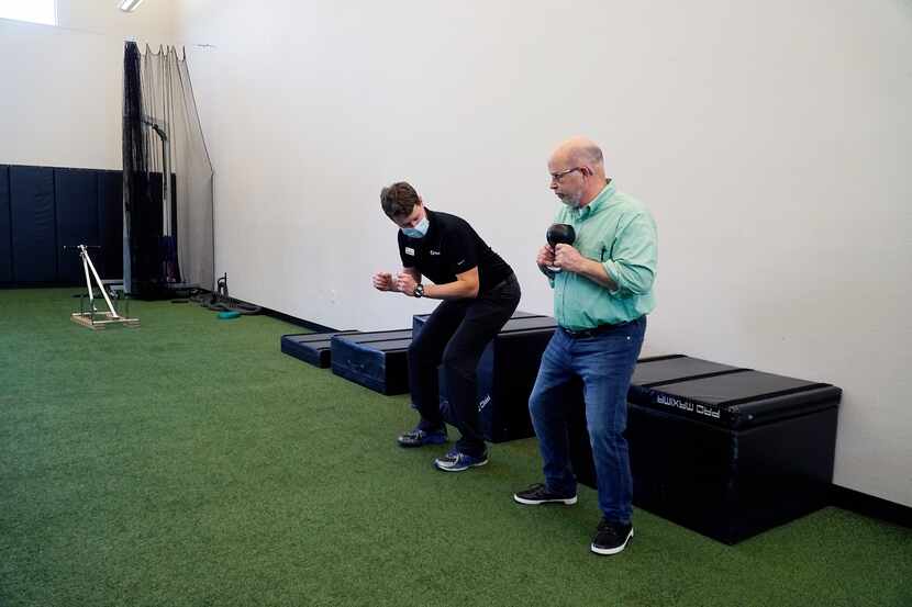 Brandon O’Malley demonstrates a box squat with former patient Scott Amon at SporTherapy in...