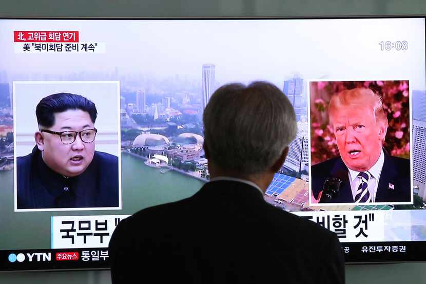 A man watches a TV screen showing file footage of U.S. President Donald Trump, right, and...