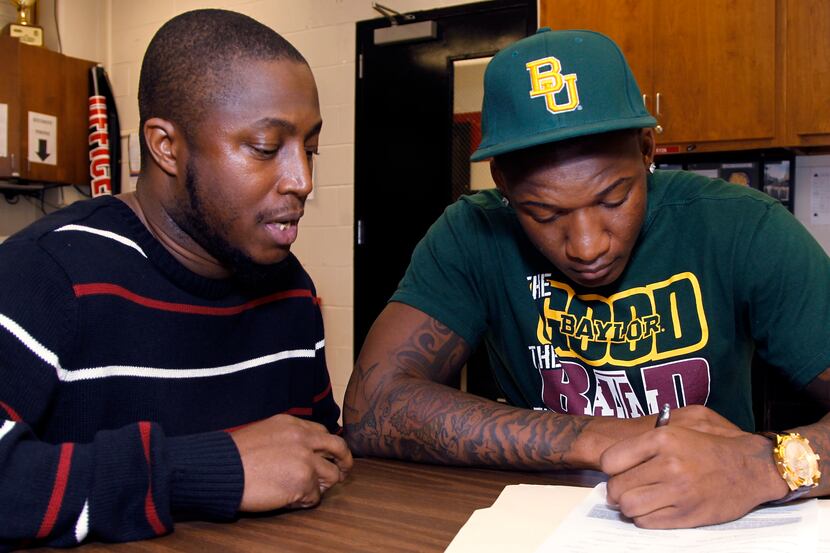 Brian Nance Sr. watches as his son, Brian Nance Jr., right, linebacker, signs his letter of...