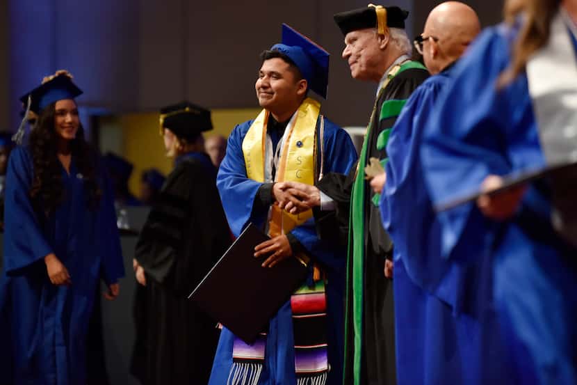 Valedictorian Hector Robledo shakes the hand of Bob Mong, president of UNT Dallas, as he...