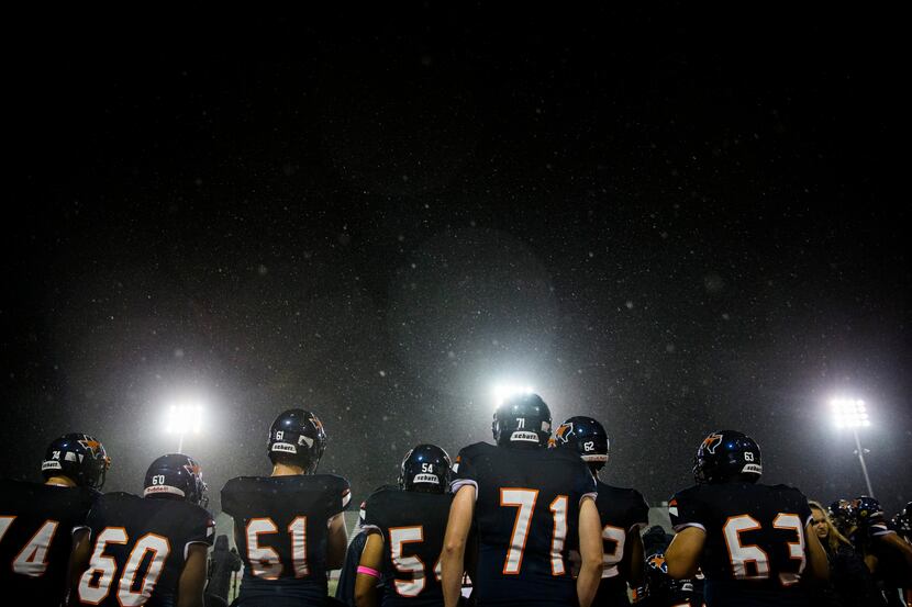 Sachse players stand on the sideline in the rain during the fourth quarter of a District...