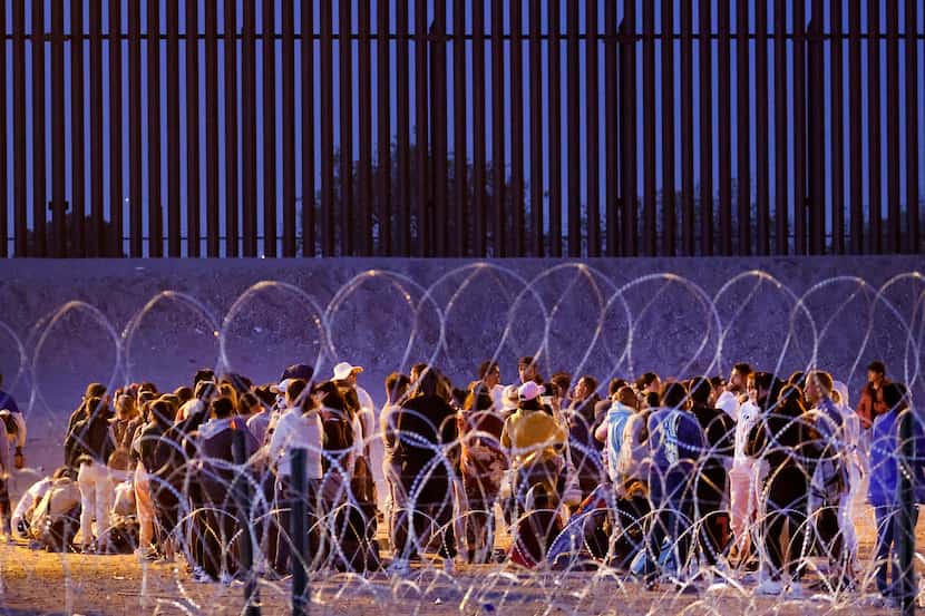 Migrants waited behind fortified concertina wire on the U.S. side of the Rio Grande river at...
