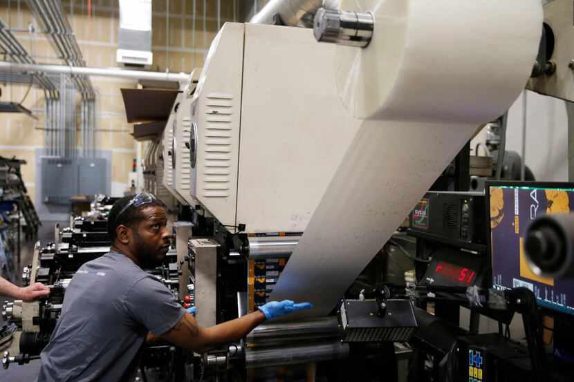 Marlon Booker works on feeding the press as he works on the flexographic press at Popular...