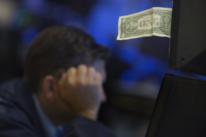 A U.S. one dollar bill is seen as a trader works on the floor of the New York Stock Exchange...