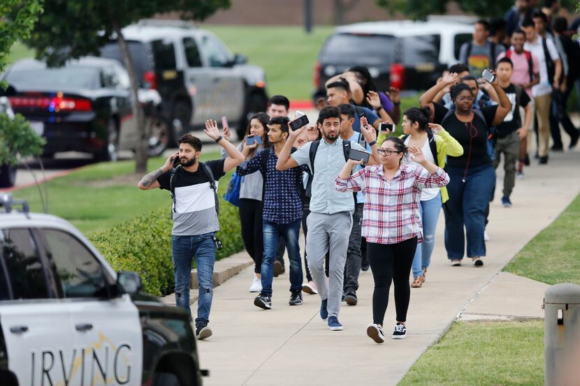 Students and faculty exit a building with their hands up after a shooting at North Lake...