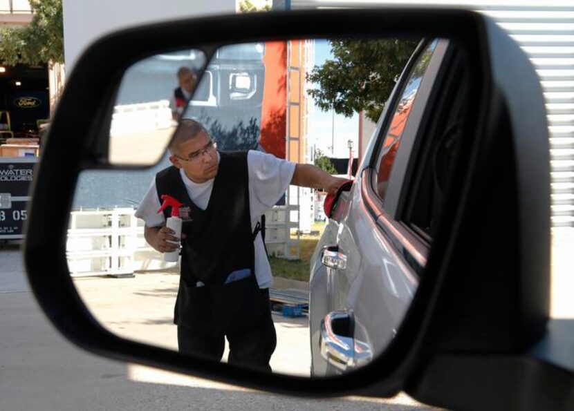 
Louis Garza wipes down the side panel of a 2015 Chevrolet Colorado, a midsize pickup that...