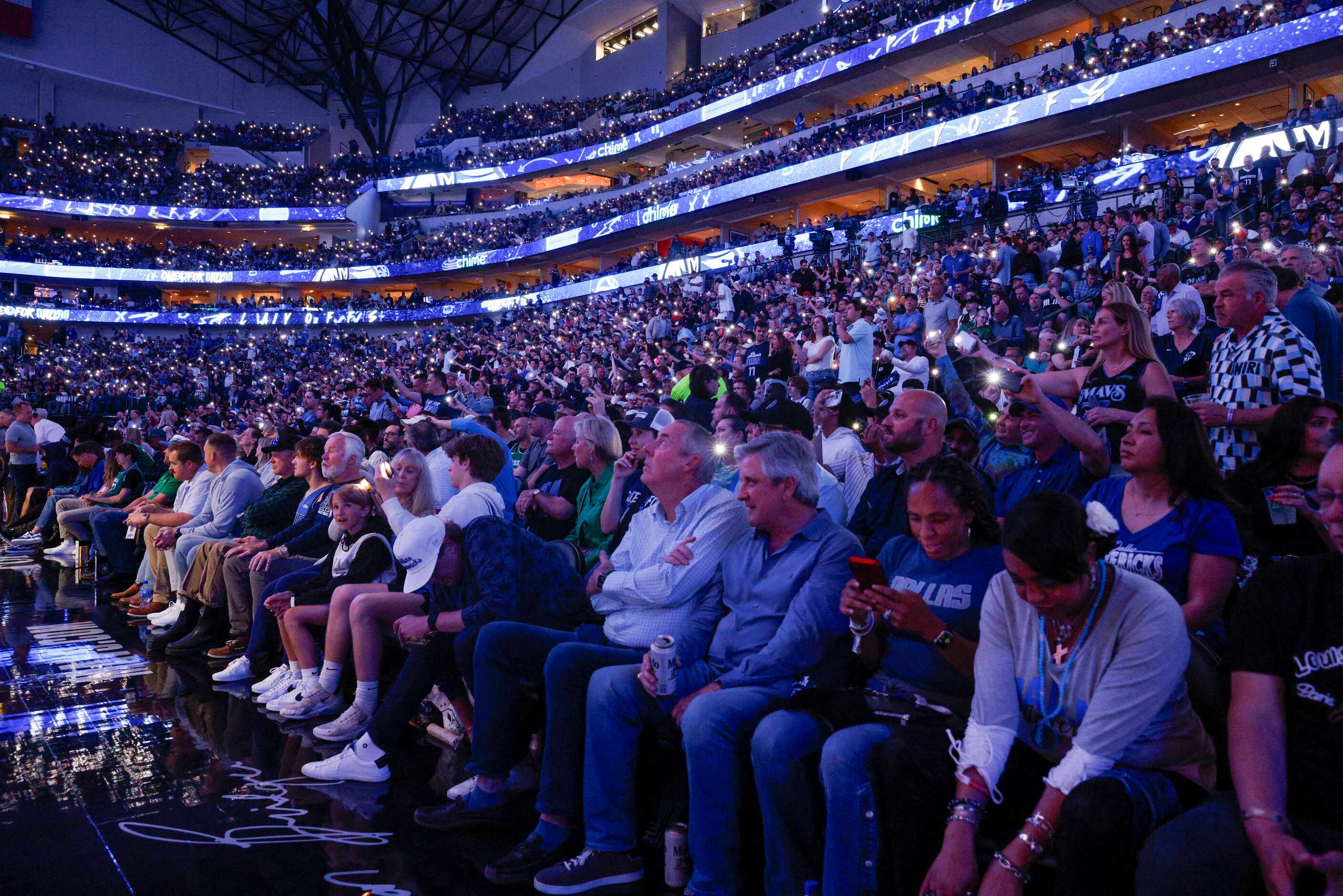 Fans hold up their phones for a chant led by Dallas Mavericks mascot Champ during the first...