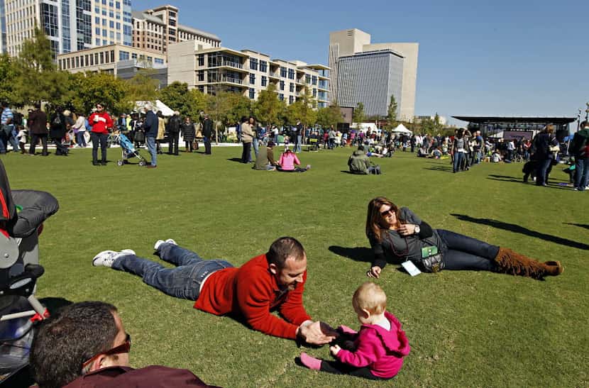 Matt Baker lies on the grass as he plays with his 11-month-old daughter, Kate Baker, at...