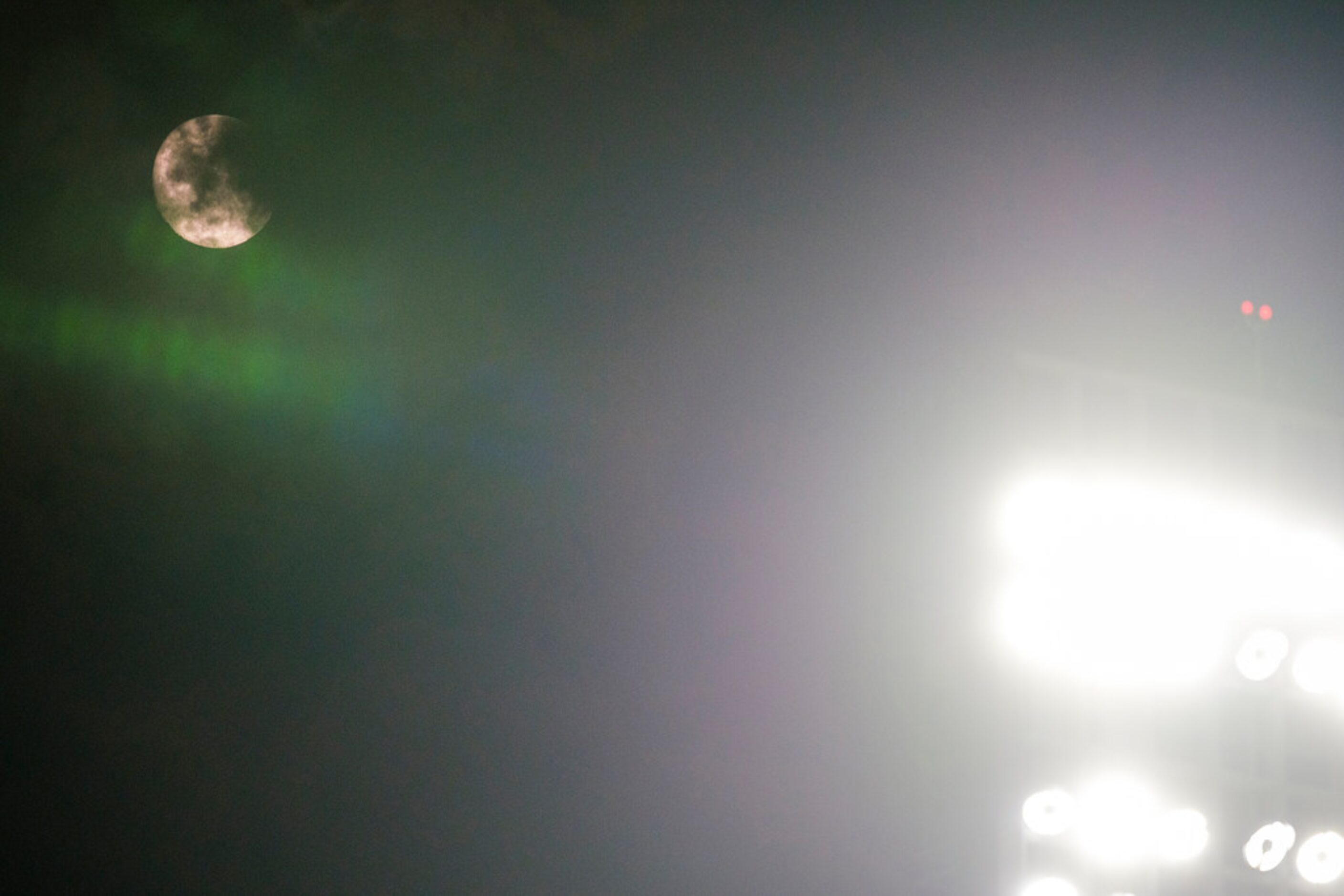 The moon rises over the lights of the stadium during the second inning of a game between...